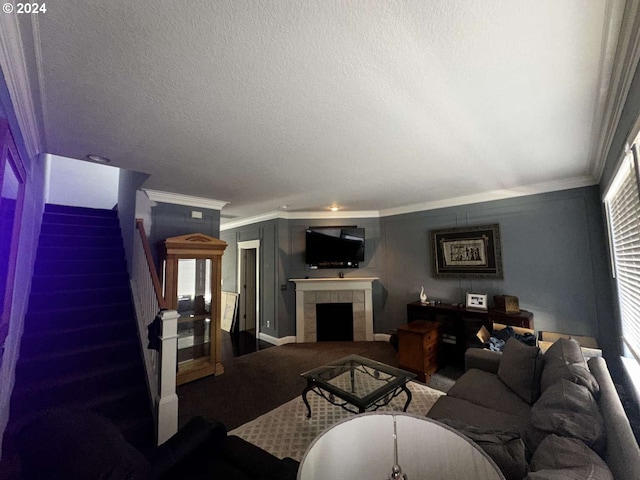 living room featuring a textured ceiling, crown molding, carpet, and a tile fireplace