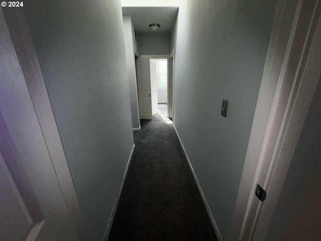 hall featuring dark carpet