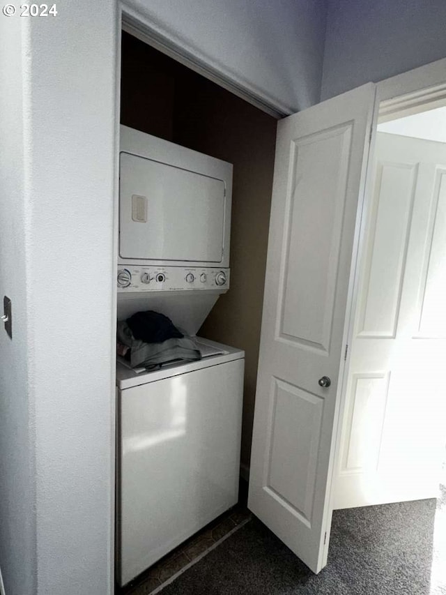 laundry room featuring stacked washing maching and dryer and dark colored carpet