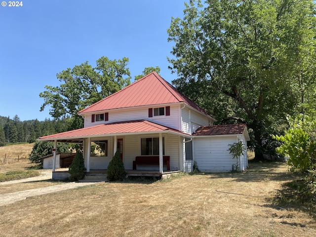 farmhouse-style home with a front yard, a porch, and a storage unit