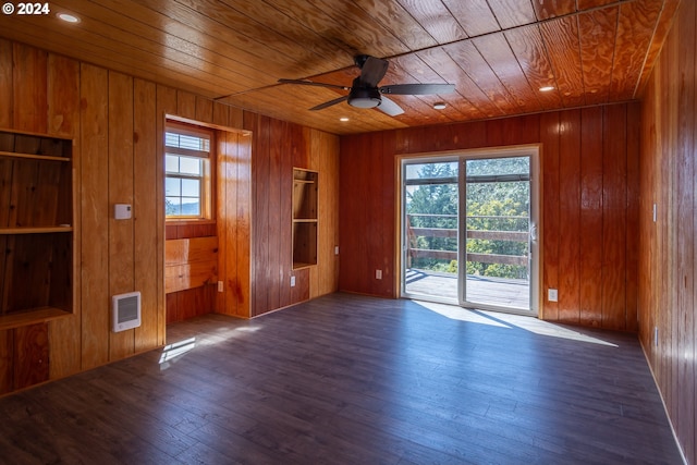 spare room with a healthy amount of sunlight, wooden ceiling, wooden walls, and dark wood finished floors