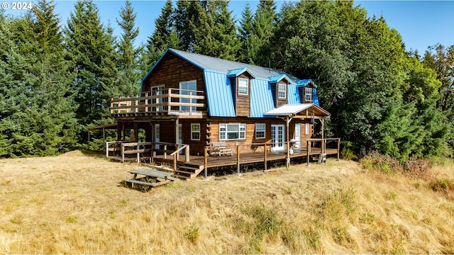 rear view of property featuring metal roof, a wooden deck, and a gambrel roof