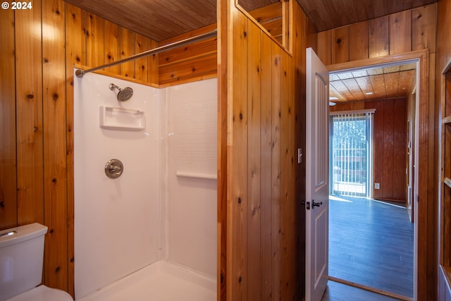 bathroom with toilet, wood walls, wood ceiling, and a stall shower