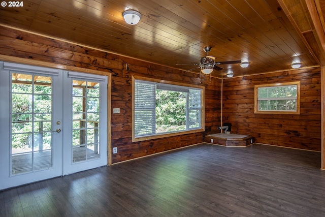 empty room with french doors, dark wood-type flooring, wood ceiling, ceiling fan, and wooden walls