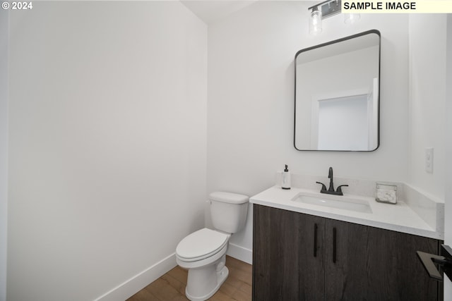 bathroom with wood-type flooring, vanity, and toilet