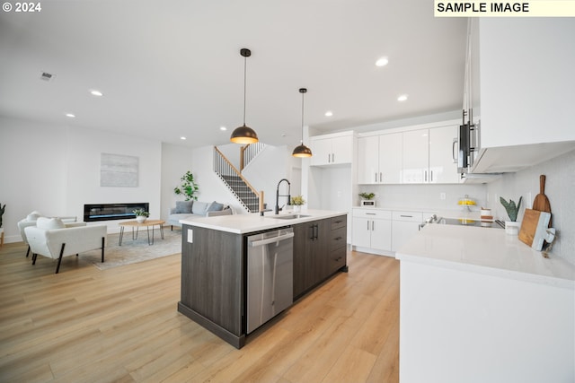 kitchen with a kitchen island with sink, sink, white cabinetry, appliances with stainless steel finishes, and decorative light fixtures