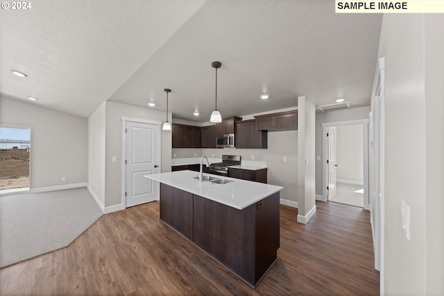 kitchen featuring appliances with stainless steel finishes, decorative light fixtures, sink, dark hardwood / wood-style flooring, and a kitchen island with sink