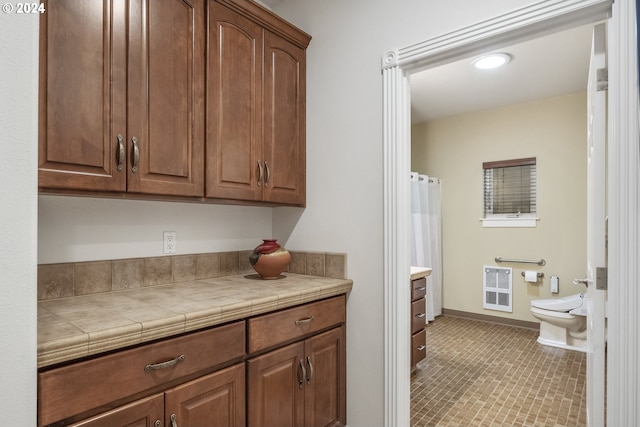 kitchen with heating unit, tile countertops, and light tile patterned floors