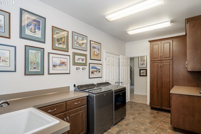 clothes washing area with sink, independent washer and dryer, and cabinets