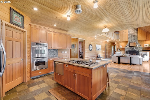 kitchen featuring wood walls, a center island, wooden ceiling, and stainless steel appliances