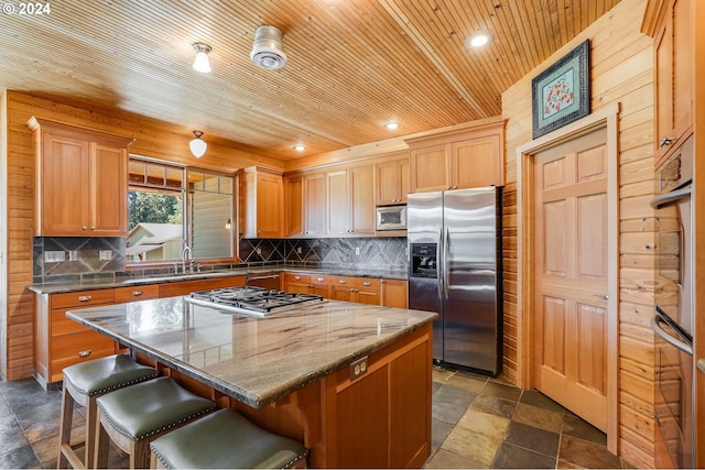 kitchen featuring a center island, stainless steel appliances, tasteful backsplash, a kitchen bar, and wood ceiling