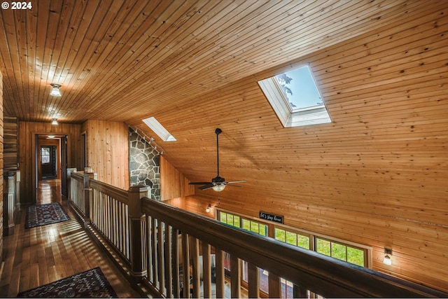 hall featuring vaulted ceiling with skylight, a healthy amount of sunlight, wood ceiling, and dark wood-type flooring