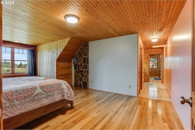 bedroom with wood walls, wooden ceiling, and light hardwood / wood-style flooring