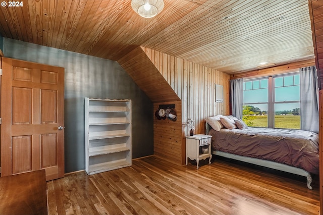 bedroom featuring lofted ceiling, wood walls, wood-type flooring, and wooden ceiling