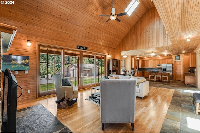 living room featuring a skylight, ceiling fan, high vaulted ceiling, and wooden ceiling