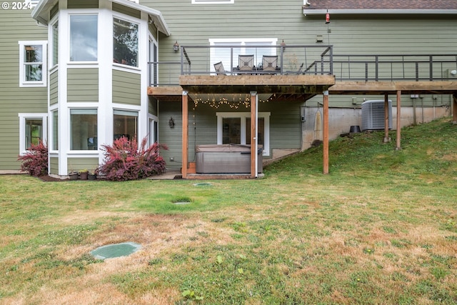 back of property with a hot tub, a yard, central AC, and a deck