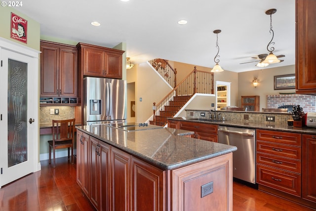 kitchen featuring tasteful backsplash, a center island, dark stone countertops, pendant lighting, and stainless steel appliances