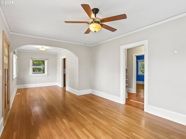 empty room with crown molding, light wood-type flooring, and ceiling fan