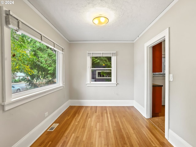 unfurnished room featuring ornamental molding, a textured ceiling, and light hardwood / wood-style floors