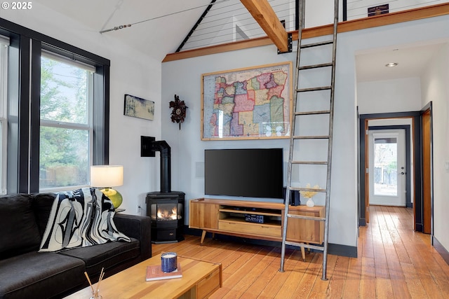 living area with lofted ceiling, hardwood / wood-style floors, a wood stove, and a healthy amount of sunlight