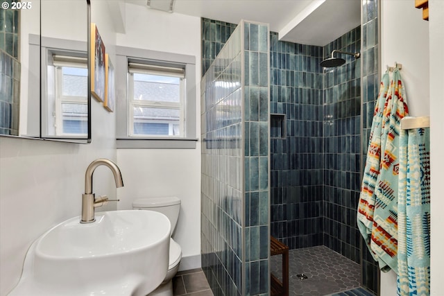 full bath featuring a sink, toilet, tiled shower, and tile patterned floors