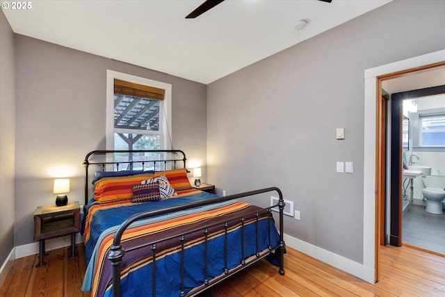 bedroom featuring hardwood / wood-style floors, a sink, a ceiling fan, and baseboards