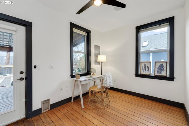 office area with light wood-style floors, visible vents, baseboards, and a ceiling fan