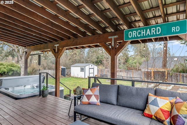 deck featuring an outbuilding, a covered hot tub, a storage shed, an outdoor hangout area, and a fenced backyard