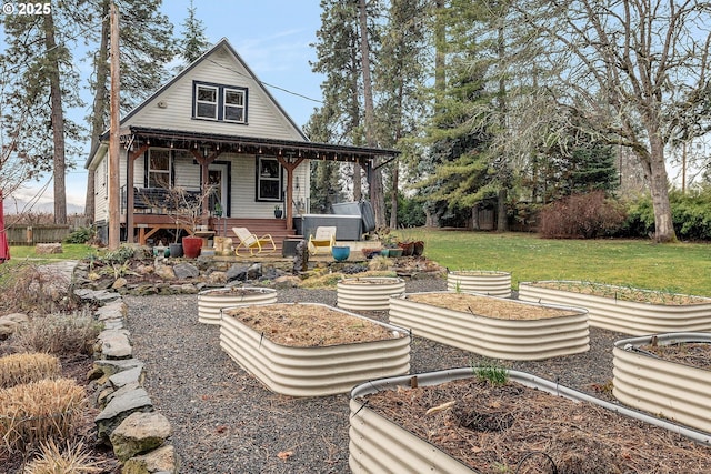 back of house featuring covered porch, a vegetable garden, and a yard