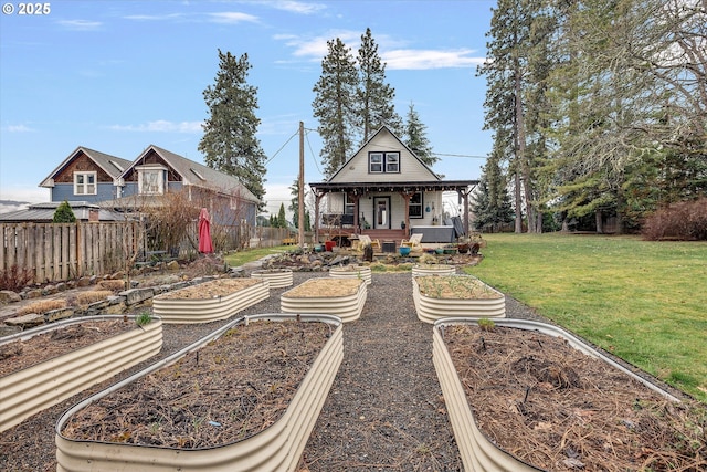 rear view of property featuring covered porch, a garden, a yard, and fence