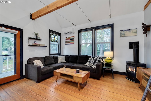 living area with a wood stove, a healthy amount of sunlight, light wood finished floors, and a wall mounted AC