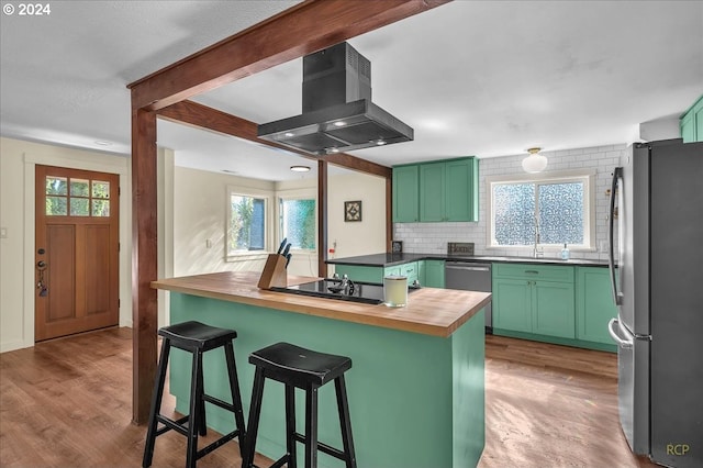 kitchen featuring stainless steel appliances, wood counters, kitchen peninsula, green cabinetry, and exhaust hood