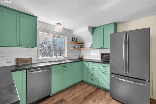 kitchen featuring dark wood-type flooring, green cabinetry, backsplash, appliances with stainless steel finishes, and sink