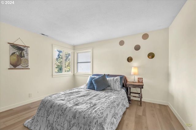 bedroom with light wood-type flooring and a textured ceiling