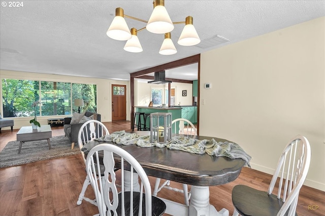 dining space featuring a textured ceiling, a chandelier, and wood-type flooring