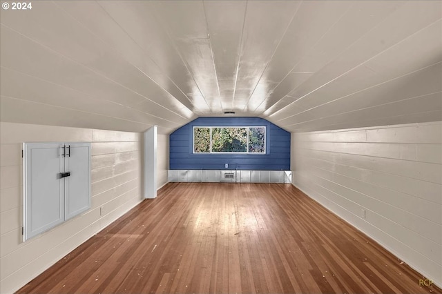 bonus room with wooden walls, hardwood / wood-style flooring, and vaulted ceiling