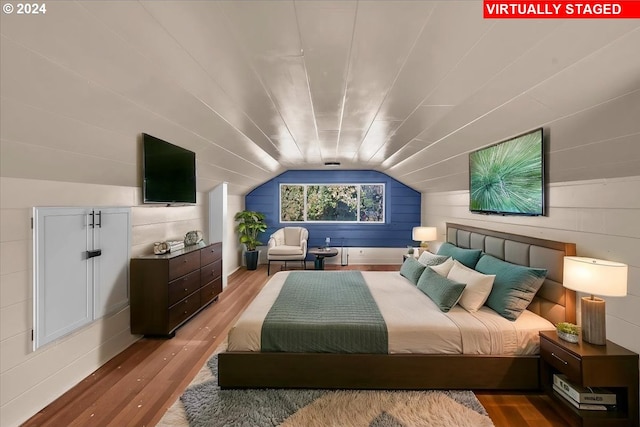 bedroom with lofted ceiling, hardwood / wood-style flooring, and wooden walls