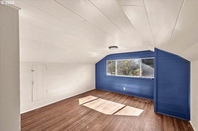 bonus room featuring dark wood-type flooring, wood walls, and vaulted ceiling