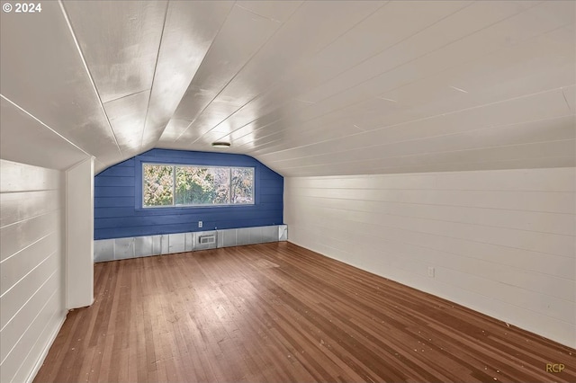 bonus room with hardwood / wood-style floors, lofted ceiling, and wood walls