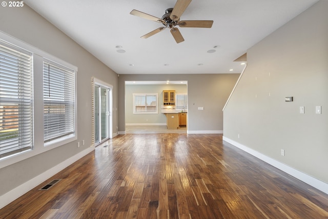 unfurnished living room with ceiling fan, a healthy amount of sunlight, and wood-type flooring