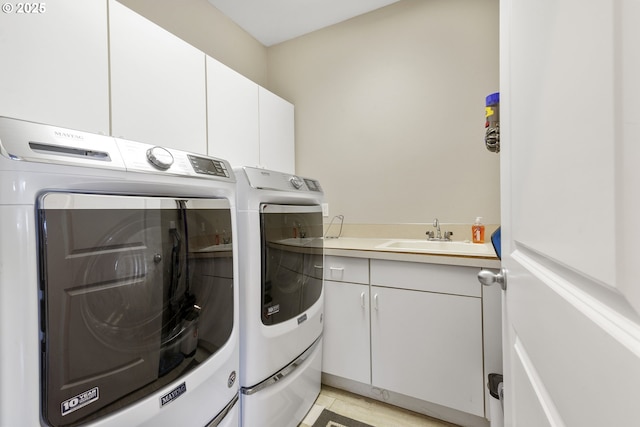 clothes washing area featuring cabinets, washing machine and dryer, and sink