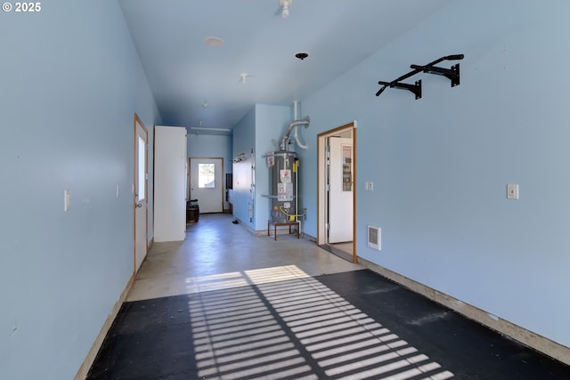 hallway featuring concrete flooring and gas water heater