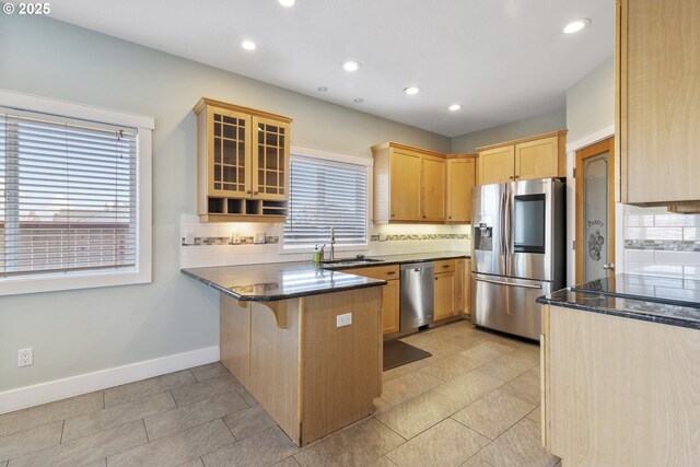 kitchen featuring light brown cabinetry, sink, dark stone countertops, kitchen peninsula, and stainless steel appliances