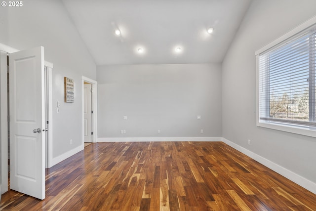 empty room with baseboards, vaulted ceiling, and dark wood-style flooring