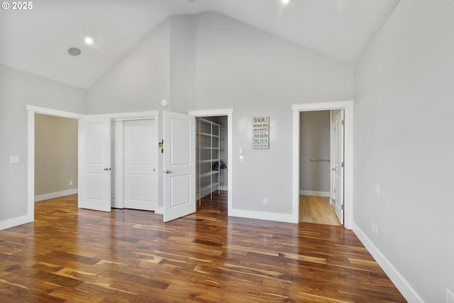 unfurnished bedroom featuring dark hardwood / wood-style flooring, high vaulted ceiling, and a closet