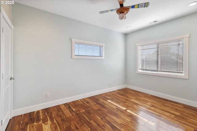 unfurnished room featuring baseboards, visible vents, ceiling fan, and wood finished floors