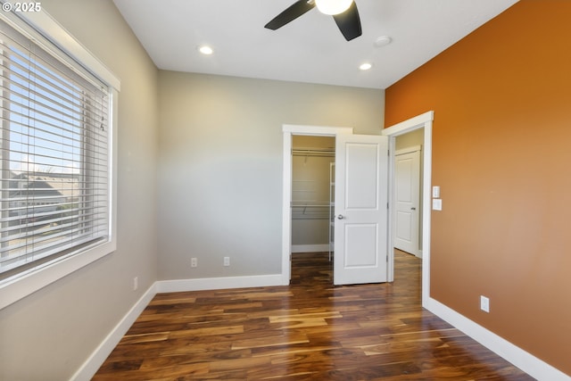 unfurnished bedroom featuring a walk in closet, dark hardwood / wood-style floors, ceiling fan, and a closet