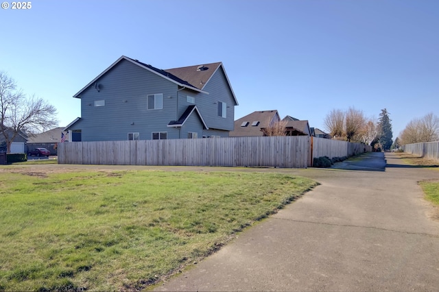 view of side of property with fence and a yard