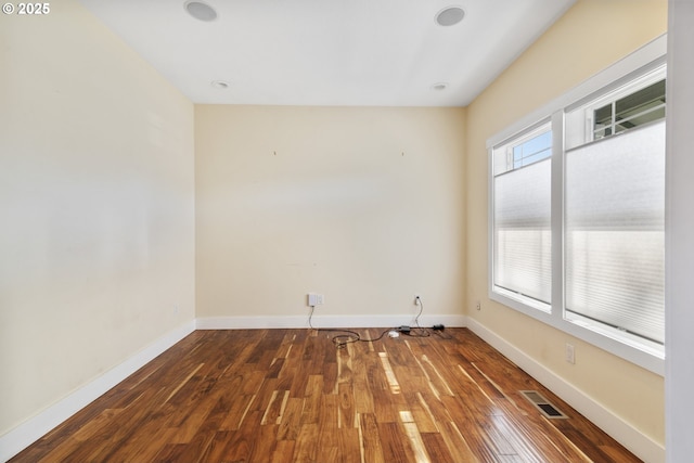 unfurnished room with hardwood / wood-style flooring, baseboards, and visible vents