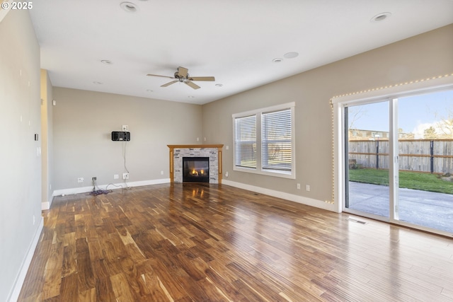 unfurnished living room with wood finished floors, a tile fireplace, and baseboards